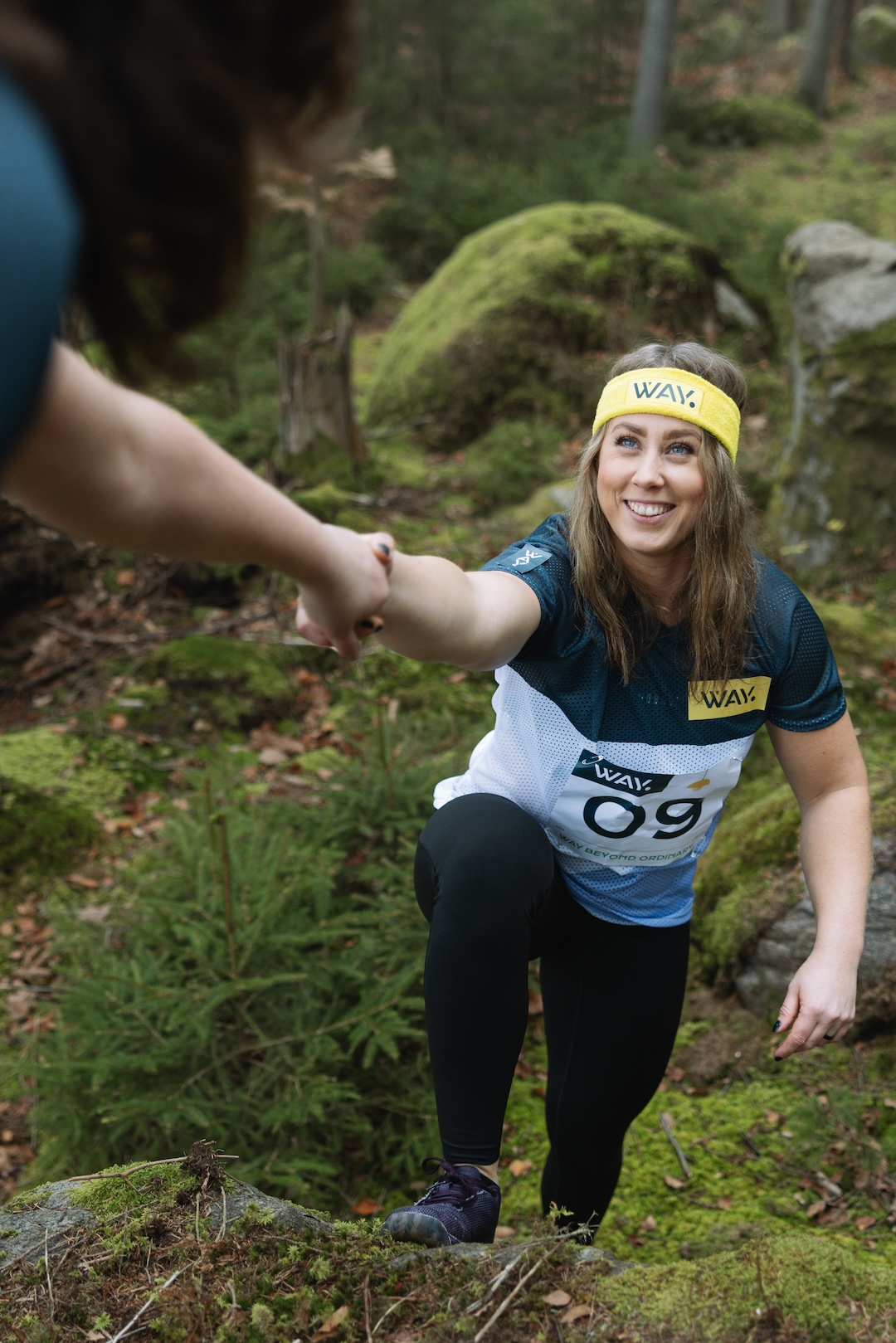 Fanny får hjälp upp på en sten i skogen